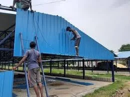 Workers installing blue roofing sheets on a CONZFRESH poultry shed frame