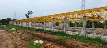 Yellow steel trusses being erected on RCC columns at a CONZFRESH farm construction site